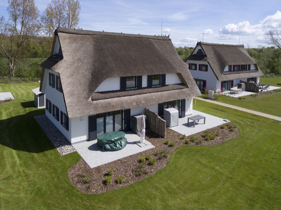 Luftaufnahme der reetgedeckten Doppelhaushälfte mit Terrasse und Garten